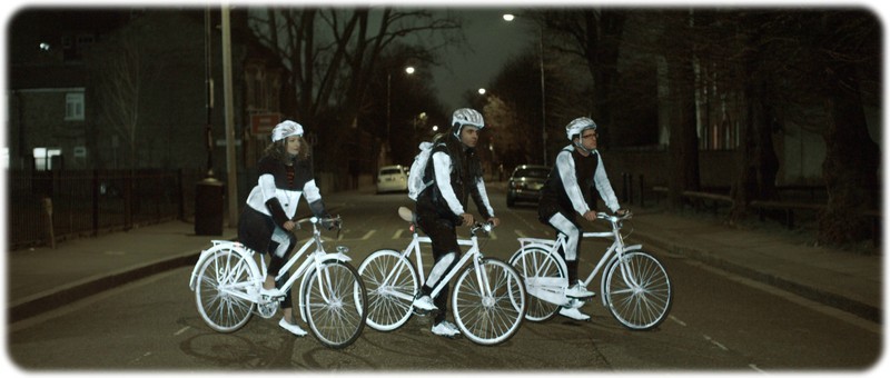 Three cylist all sat on their bike at night with the reflective life paint on thier bikes,shoes,helmet and clothes 