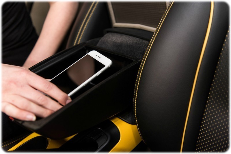 someone is shown putting a phone into the signal shiel armrest inside the car. 