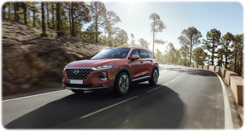 New 2018 Hyundai Santa Fe on the road driving front view in a red colour.