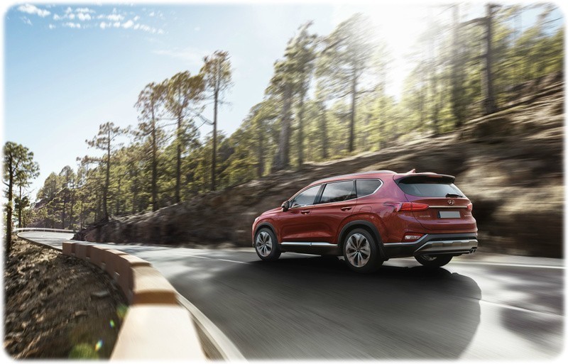 New 2018 Hyundai Santa Fe on a forest mountain road rear die view driving away 