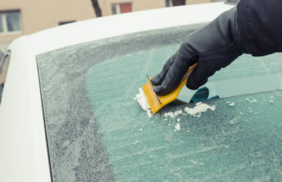 Person scraping frozen rear window of car